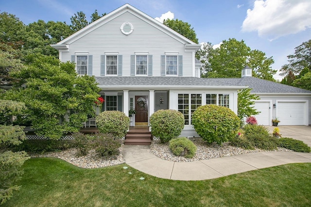 view of front of home with roof with shingles, an attached garage, concrete driveway, a front lawn, and a chimney