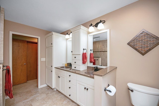 full bathroom featuring a sink, double vanity, toilet, and baseboards