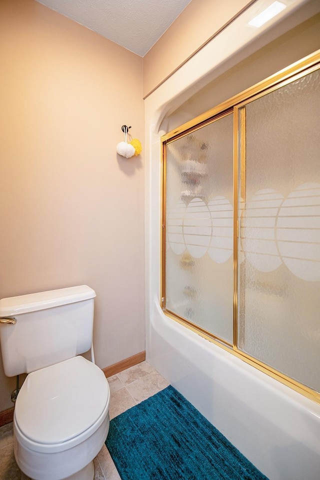 bathroom featuring toilet, baseboards, and bath / shower combo with glass door