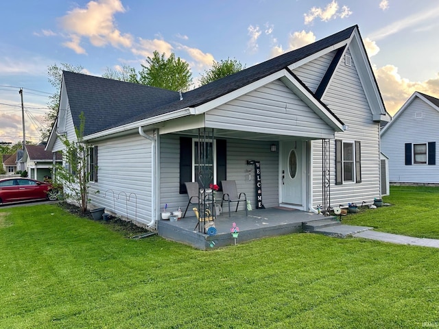 bungalow featuring a porch, roof with shingles, and a front lawn