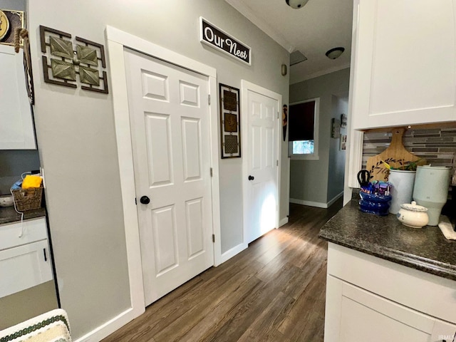 kitchen featuring white cabinets, crown molding, dark wood-type flooring, and backsplash