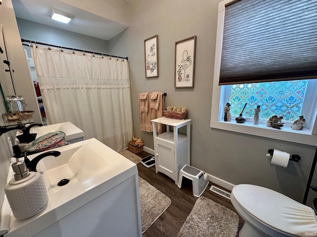 bathroom featuring vanity, baseboards, visible vents, and wood finished floors
