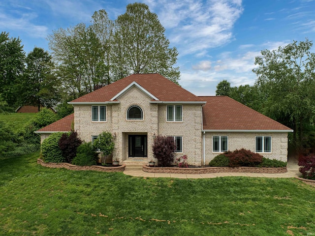 colonial home featuring a front yard and brick siding
