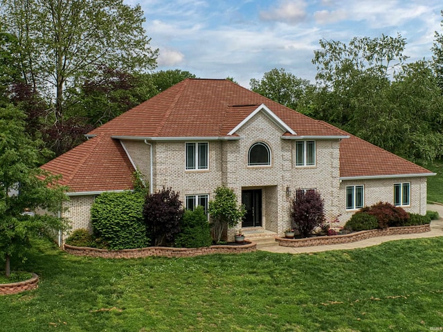 colonial inspired home with brick siding and a front lawn