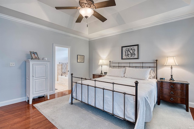 bedroom with baseboards, a tray ceiling, crown molding, and wood finished floors