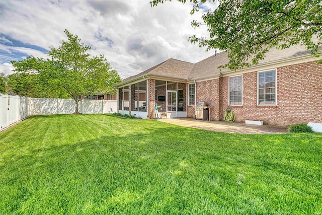back of house featuring a patio, a sunroom, a yard, a fenced backyard, and brick siding