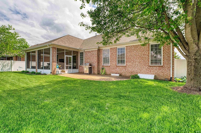 rear view of property featuring a yard, a sunroom, fence, and brick siding