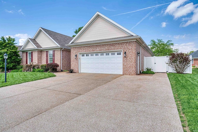 ranch-style home with a gate, a front lawn, brick siding, and driveway