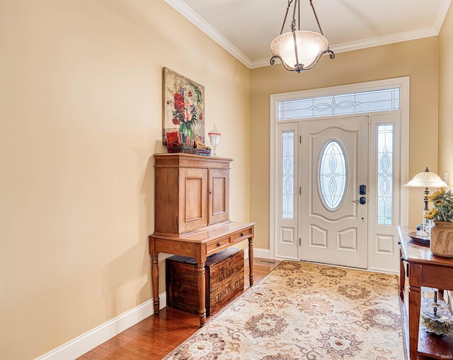 entrance foyer featuring baseboards, crown molding, and wood finished floors