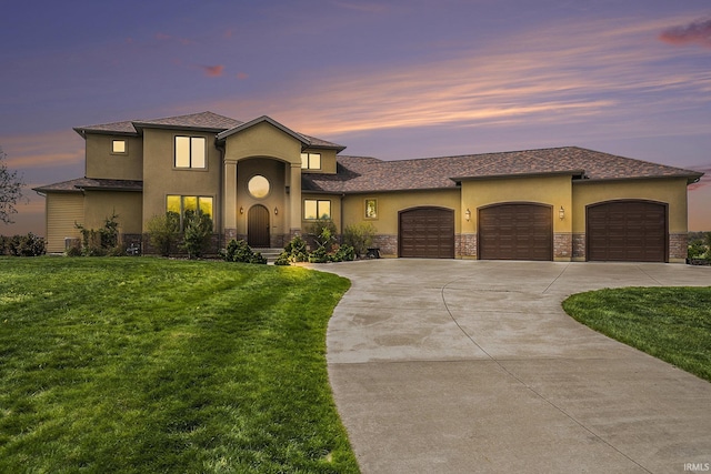mediterranean / spanish home featuring stone siding, stucco siding, a front lawn, and an attached garage