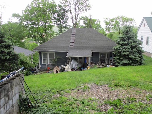 back of house featuring a shingled roof and a lawn