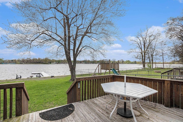 deck with a water view, fence, a playground, and a lawn
