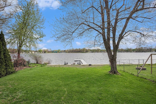 view of yard featuring a dock, a water view, and fence
