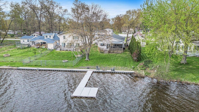dock area featuring a fenced backyard, a deck with water view, a residential view, and a lawn
