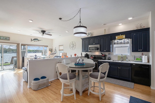 kitchen with a sink, light wood finished floors, light countertops, a ceiling fan, and appliances with stainless steel finishes