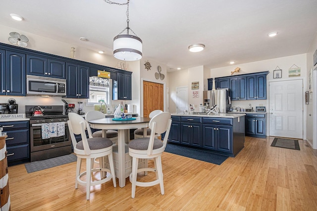 kitchen with light wood-type flooring, a center island with sink, stainless steel appliances, and blue cabinets