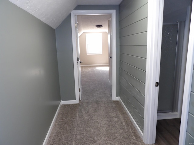 hallway with lofted ceiling, baseboards, and carpet