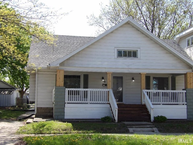 bungalow featuring a porch and roof with shingles