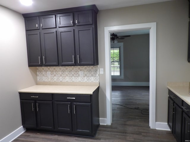 kitchen with a ceiling fan, dark wood finished floors, baseboards, light countertops, and decorative backsplash