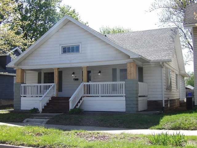 bungalow featuring covered porch, roof with shingles, and stairway