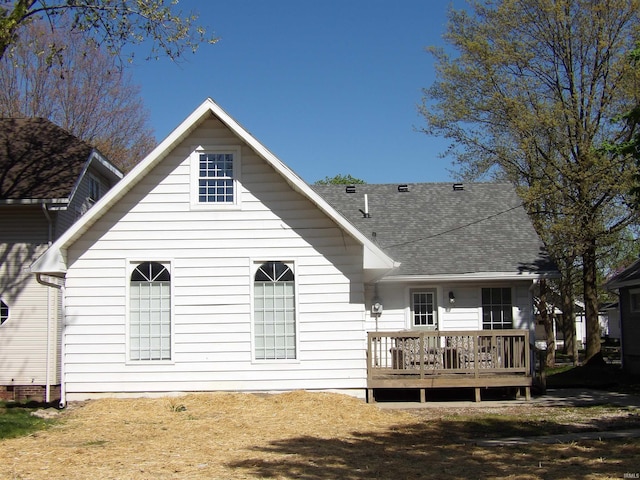 rear view of property with a deck and roof with shingles