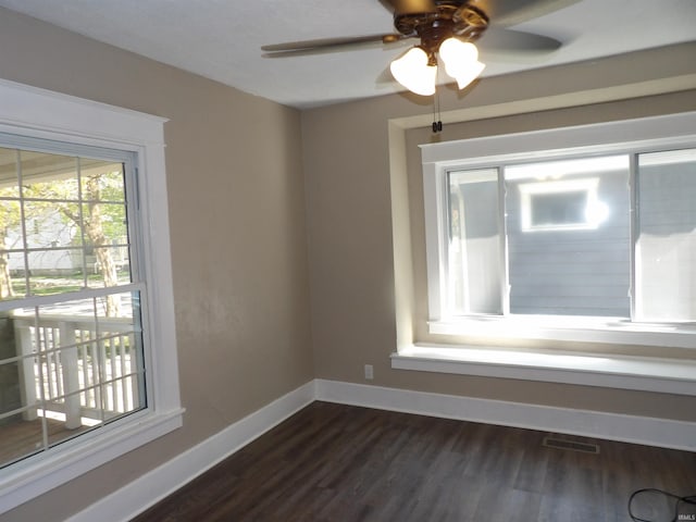 empty room featuring visible vents, baseboards, a ceiling fan, and dark wood-style floors