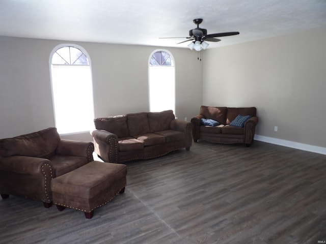 living room featuring baseboards, ceiling fan, and dark wood-type flooring