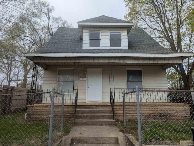 bungalow-style home with a porch, roof with shingles, and a fenced front yard