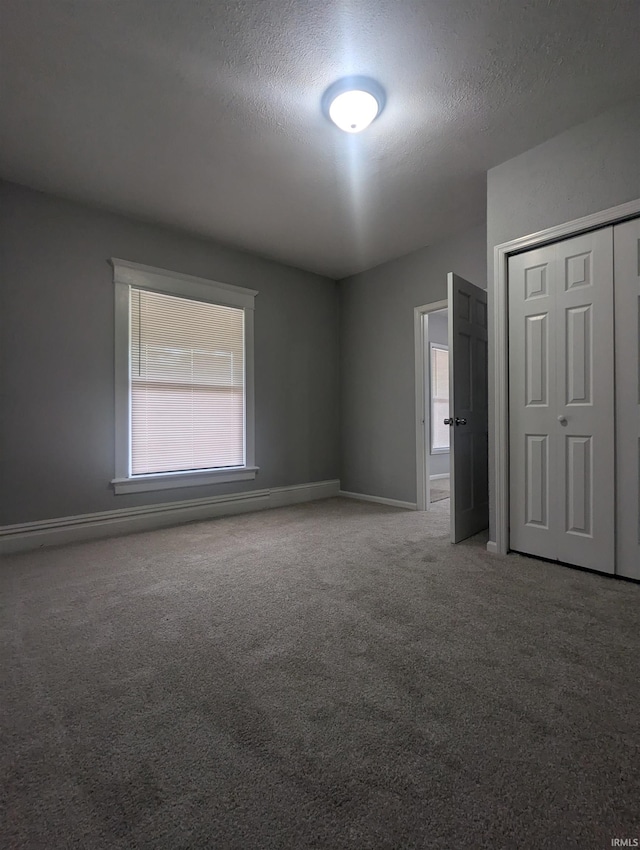 unfurnished room featuring carpet flooring, a textured ceiling, and baseboards