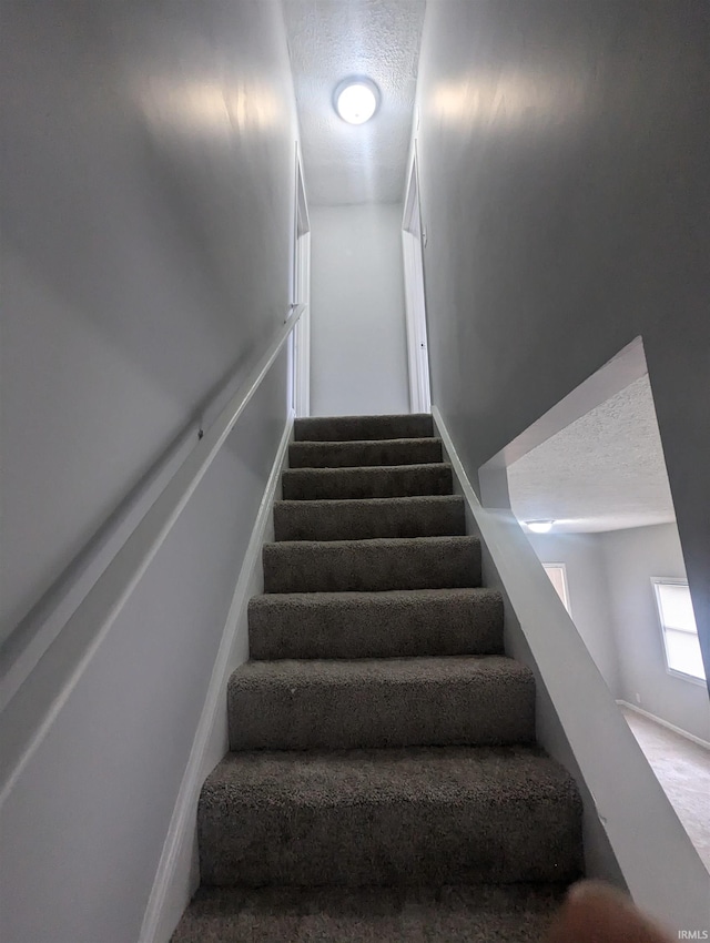 stairs featuring a textured ceiling