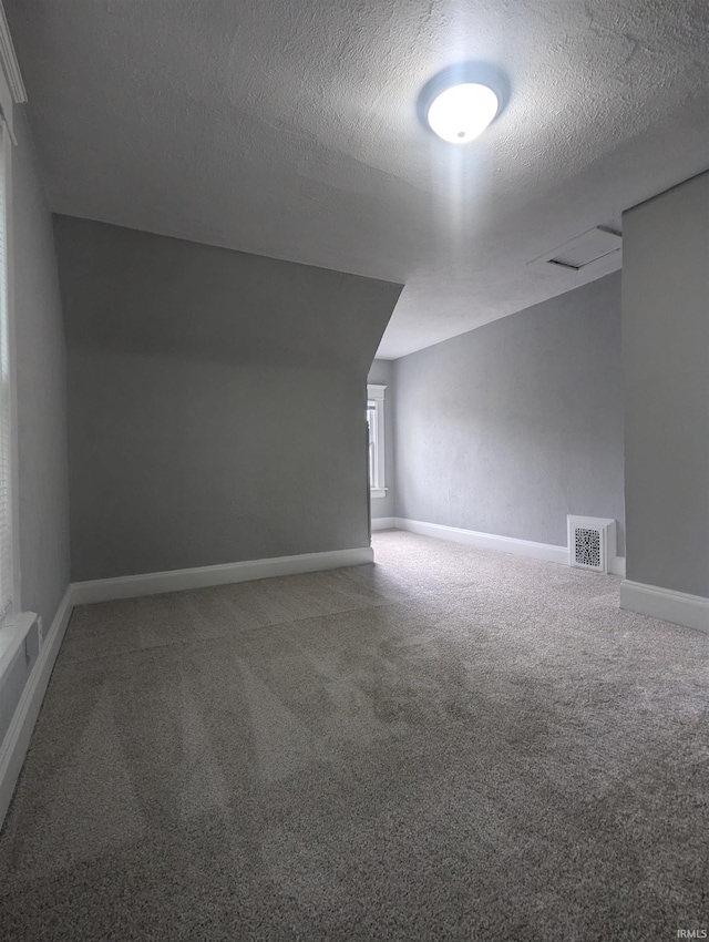 bonus room featuring a textured ceiling, baseboards, visible vents, and carpet floors
