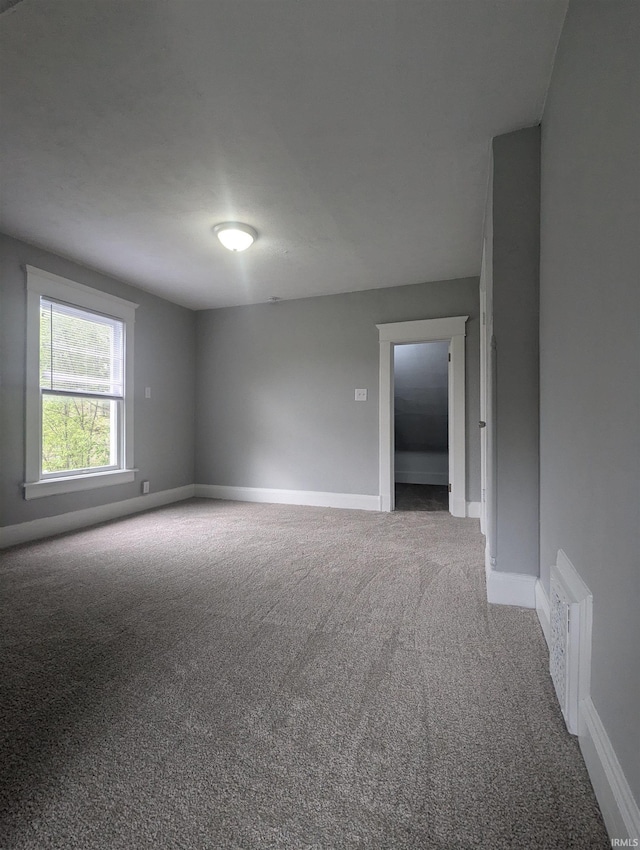 carpeted spare room with visible vents and baseboards