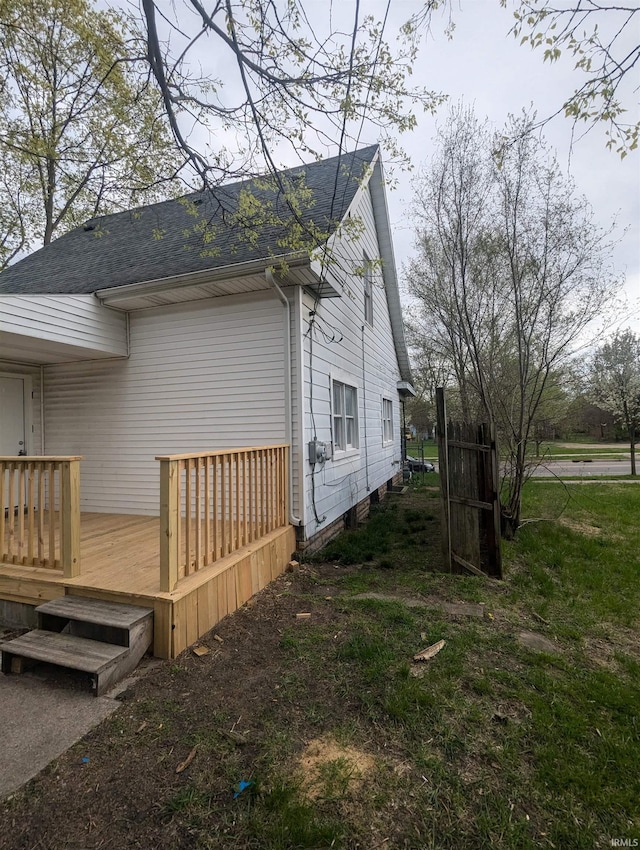 view of home's exterior featuring a wooden deck and roof with shingles