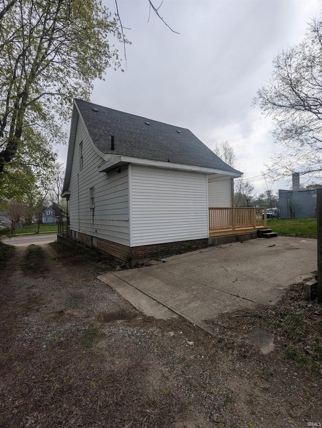 rear view of property with a wooden deck and roof with shingles