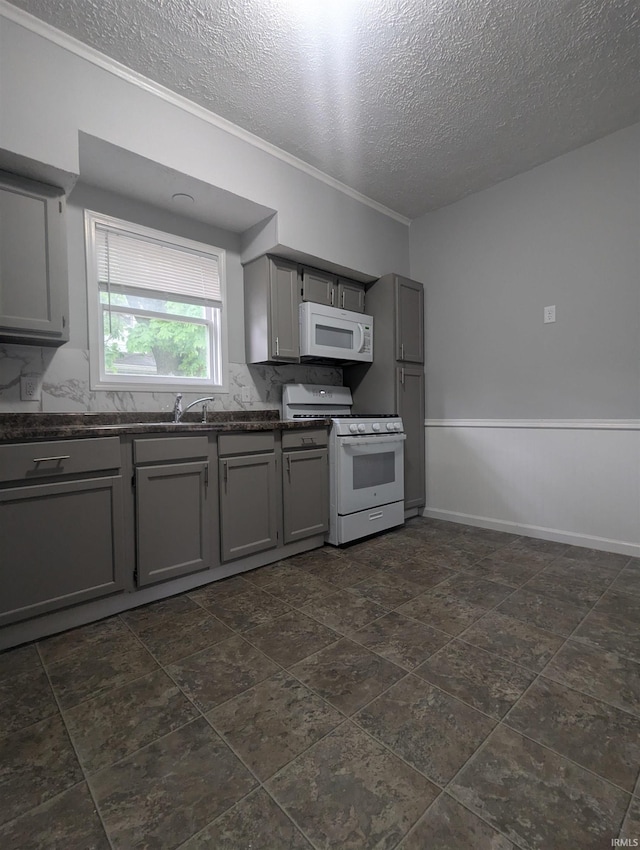 kitchen featuring a textured ceiling, white appliances, ornamental molding, dark countertops, and gray cabinets