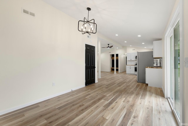 unfurnished dining area featuring vaulted ceiling, a wealth of natural light, light wood-type flooring, and visible vents