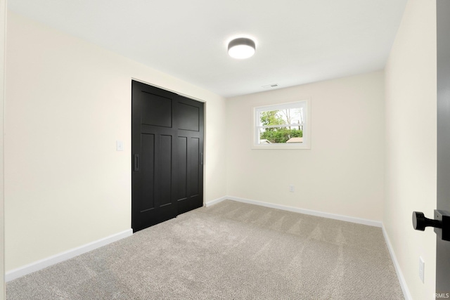 unfurnished bedroom featuring baseboards, light carpet, a closet, and visible vents