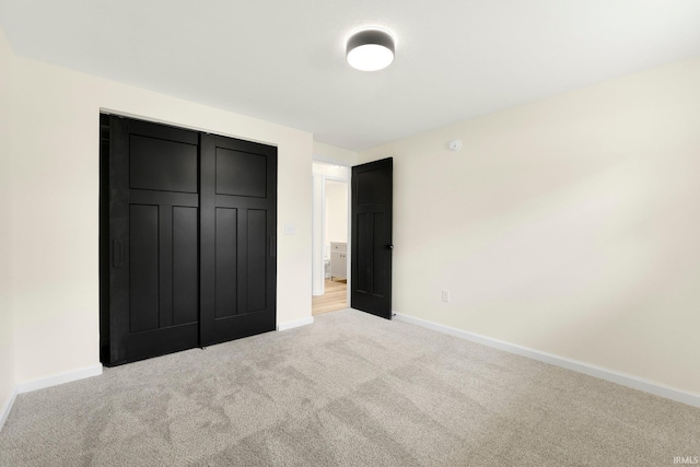 unfurnished bedroom with light colored carpet, baseboards, and a closet