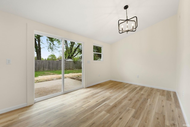 unfurnished dining area with lofted ceiling, baseboards, a chandelier, and light wood-style flooring