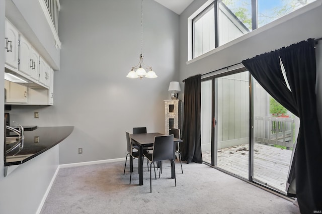 9404 S Lake Ridge Dr, Bloomington, IN 47401 - dining area with light colored carpet, a towering ceiling, baseboards, and an inviting chandelier