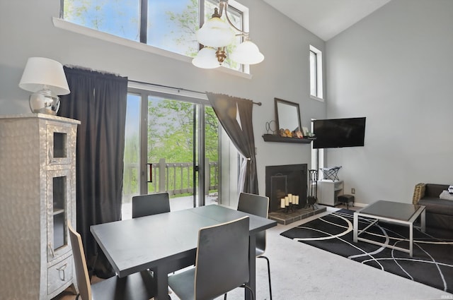 9404 S Lake Ridge Dr, Bloomington, IN 47401 - carpeted dining room with a notable chandelier, plenty of natural light, high vaulted ceiling, and a fireplace with raised hearth