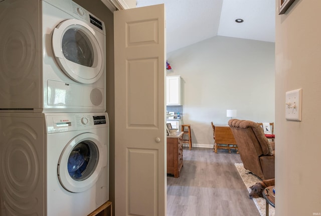 laundry room featuring stacked washer and clothes dryer, laundry area, light wood finished floors, and baseboards