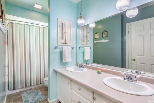 bathroom featuring double vanity, toilet, a shower with shower curtain, and a sink