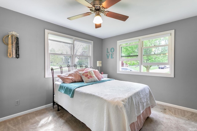carpeted bedroom with multiple windows, baseboards, and a ceiling fan