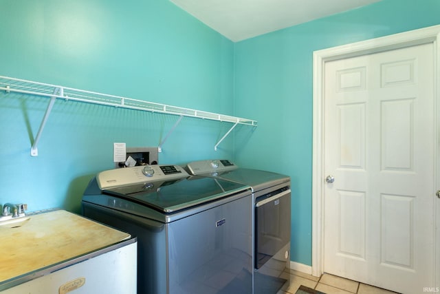 laundry area with a sink, laundry area, washer and clothes dryer, baseboards, and light tile patterned flooring