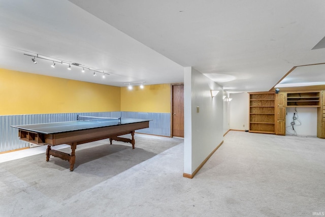 recreation room with carpet flooring, rail lighting, and wainscoting