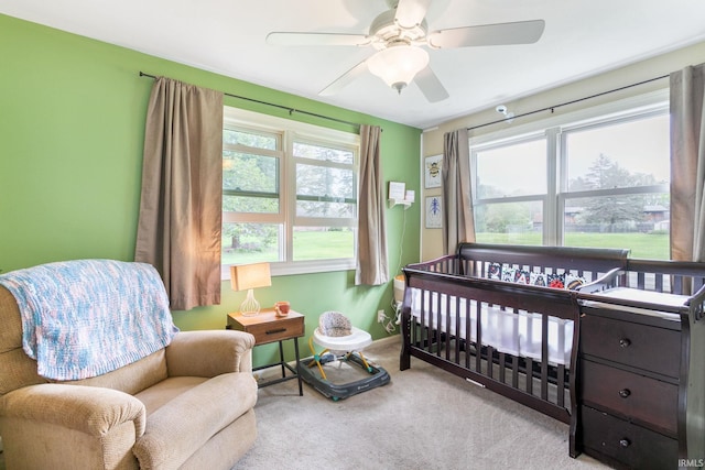 bedroom featuring baseboards, carpet flooring, ceiling fan, and a nursery area