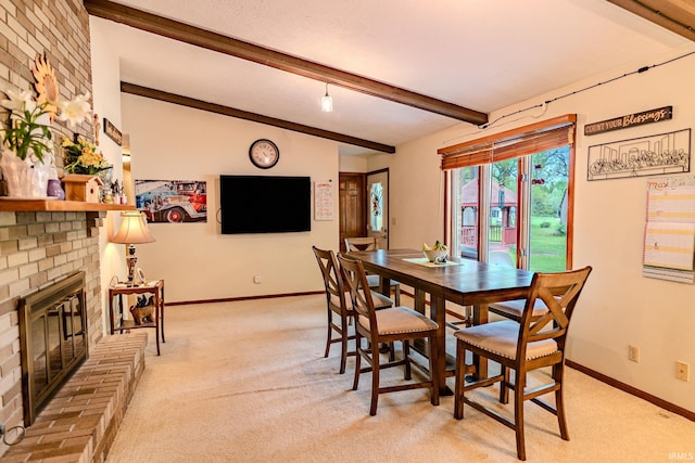 dining room featuring baseboards, beamed ceiling, light carpet, and a brick fireplace