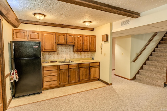 kitchen featuring a sink, freestanding refrigerator, visible vents, light countertops, and light carpet