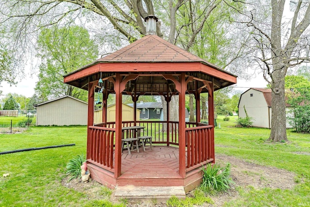 wooden terrace featuring a storage unit, a gazebo, an outdoor structure, and a lawn